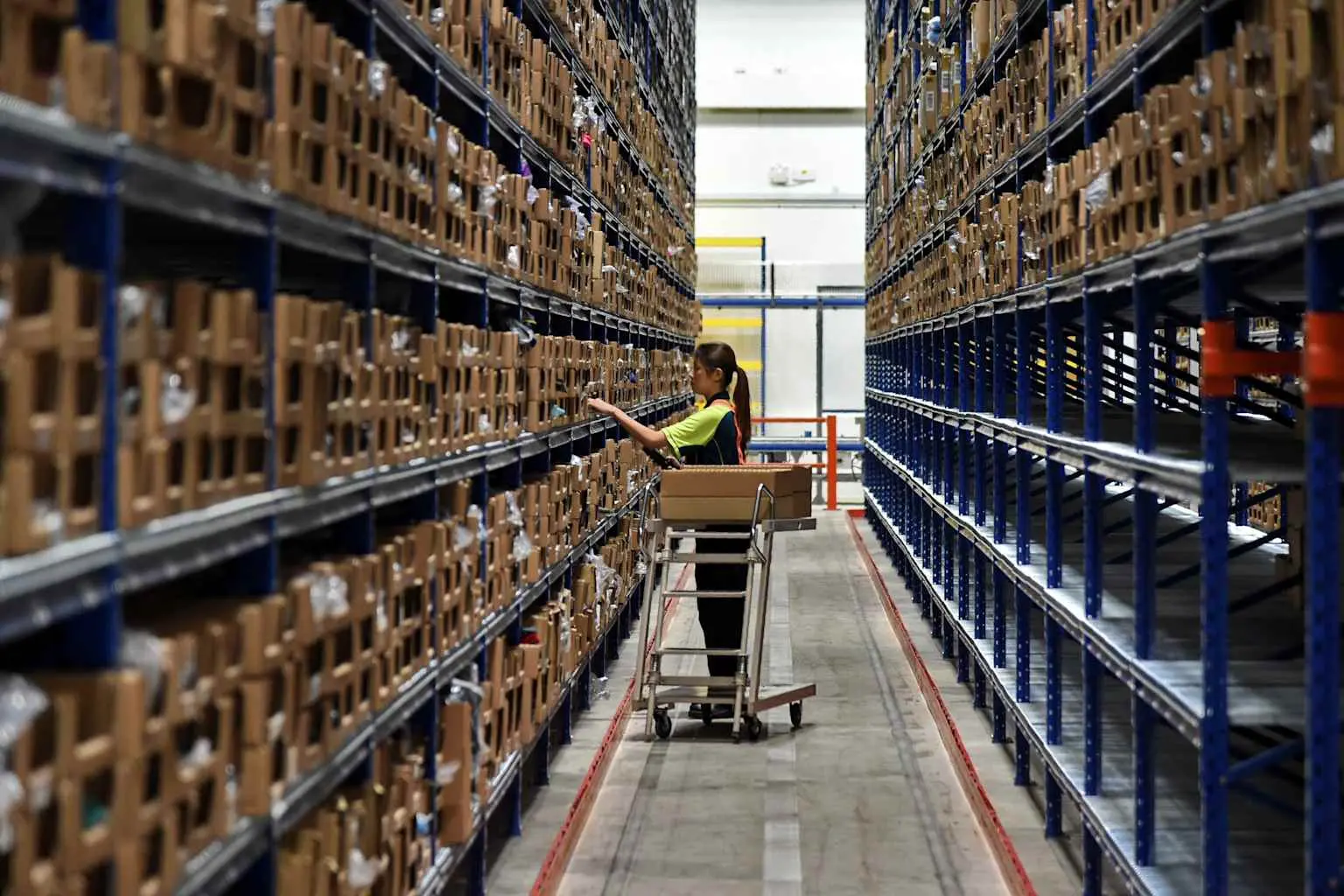 Worker in hi-vis vest retrieving boxes in fulfillment warehouse